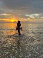 Thailand, a beautiful sunset over the sea with a girl emerging from the water.