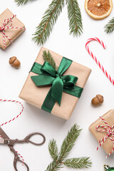 Obraz premium Christmas composition with gift boxes, fir tree branches, threads and scissors on white background, closeup