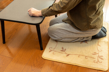 床に敷いたカーペットの上に正座で座る男性