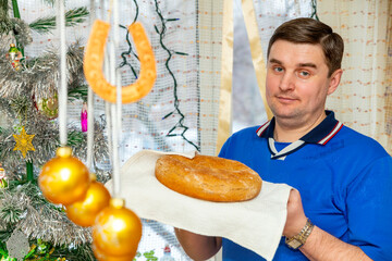 handsome young man holding freshly baked bread in his hands for New Year's holiday