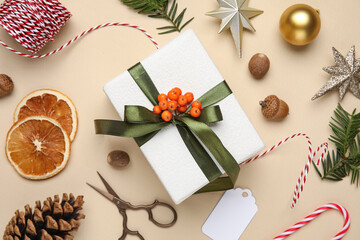 Christmas gift box with rope, scissors, fir tree branches and decor on beige background