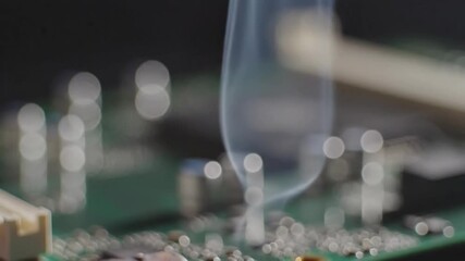Soldering iron tip heating on electronic circuit board emitting smoke during assembly or repair process - Powered by Adobe