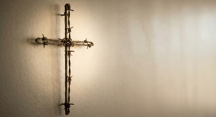 Cross made of twigs hanging on a light wall for religious symbolism  