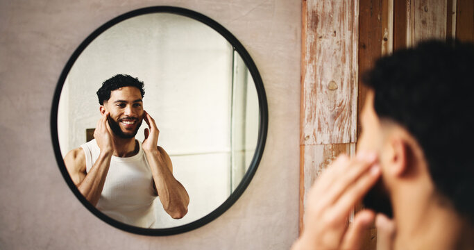 Happy man, grooming and hygiene with mirror in bathroom for morning routine or cosmetics in home. Male person, reflection or cleaning with smile, facial treatment or skincare for smooth skin in house