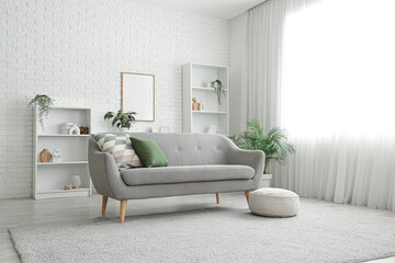 Soft pouf and comfortable grey sofa with pillows in living room