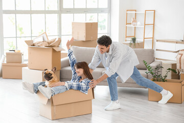 Young couple with French bulldog having fun in rented apartment on moving day