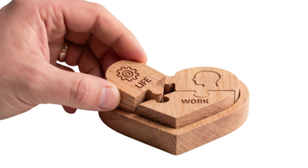 Hand places a wooden puzzle piece into a heart-shaped puzzle representing work-life balance concept