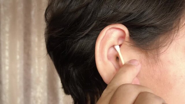 Teenage boy cleaning ear with cotton swab close-up. Wooden cotton buds. Hygiene
