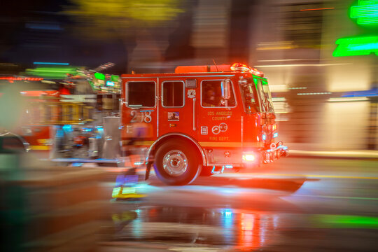 LOS ANGELES, CA - September 30, 2025: Fire engine truck speeding through traffic on a city street at night. Long exposure photo with blurred background.