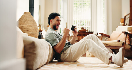 Phone, man and celebration in home for win, online betting or game victory on floor. Mobile, excited person and success with fist pump in living room for gambling achievement, goal and lottery © OnPoint/peopleimages.com