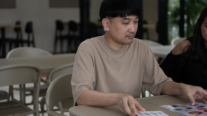 Man looking at a food menu while sitting at an outdoor cafe, deciding what to order.