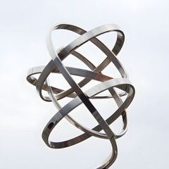 Metallic rings intertwine against a bright sky creating a modern abstract sculpture art piece