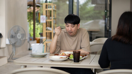 Man eating lunch at an outdoor cafe table, focused on his meal in a simple casual dining setting.