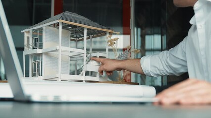 Closeup of skilled caucasian architect engineer hand compare house design between model and blueprint in laptop. Professional project manager using laptop analysis data. Focus on hand. Manipulator. - Powered by Adobe
