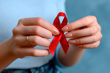 Woman hands holding red ribbon for World AIDS Day awareness