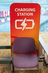 Charging station at Changi Airport in Singapore with a bright red sign featuring a battery icon and a lightning bolt symbol. 