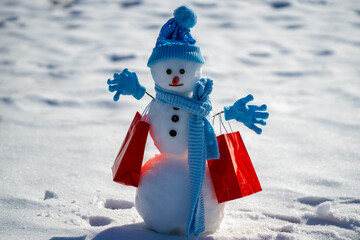 Snowman with shopping bags during a winter sale. Winter shopping fun. Snowman promoting Christmas gift. Snowman with winter discount sale. Winter seasonal sales. Snowman presenting Christmas gift.
