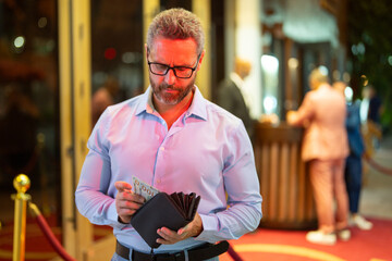 Rich business man holding wallet with money. Rich businessman counting dollars bills money. Wealthy rich man with a wallet and money cash. Businessman in urban nightlife hold wallet. Rich lifestyle.