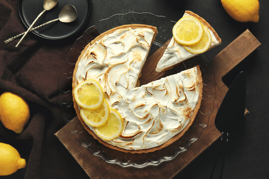 Plate with tasty lemon pie on black grunge background, closeup