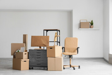 Moving boxes with wrapped computer monitor and furniture in office