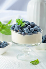 Panna cotta with fresh blueberries in a clear bowl.