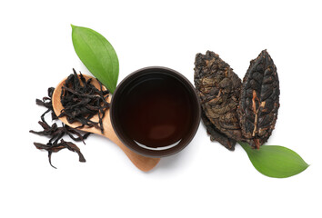 Dry pressed puer leaves with wooden spoon and cup of tea on white background