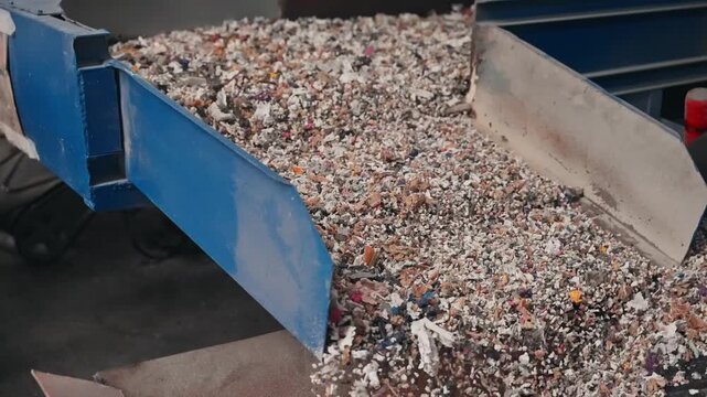 Shredded recycled rubber transported on conveyor inside industrial facility
