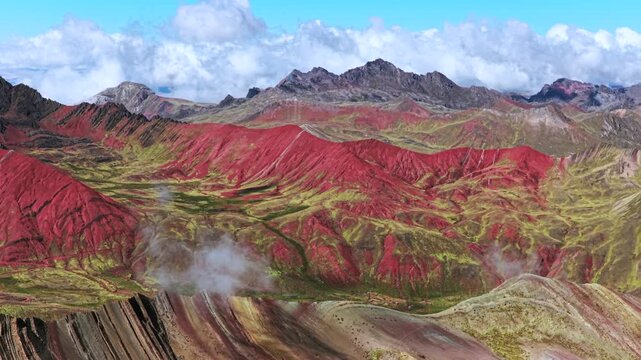 Rainbow Mountain Red Valley fog trek Vinicunca Monta&ntilde;a de Siete Colores Peru aerial drone view Peruvian Andes seven colored mountains melted glacier Vilcanota Cusco Region morning blue sky pan left