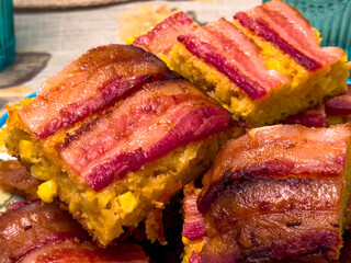 Macro close-up of bacon-topped cornbread casserole bars, showing crispy bacon and moist cornbread texture. Perfect for comfort food, holiday meals, and southern cuisine themes.