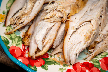 Close-up of sliced cooked turkey breast arranged on a colorful floral plate, showcasing tender texture and warm seasoning. Ideal for food, cooking, meal prep, and holiday themes.