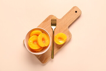 Bowl with sweet canned peaches on beige background