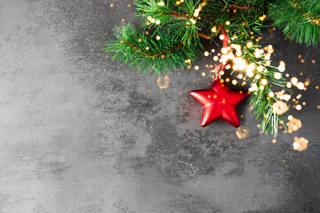 Single Red Christmas glass red hanging from afir branchon black concrete background, Festive greeting card, design with copy space.