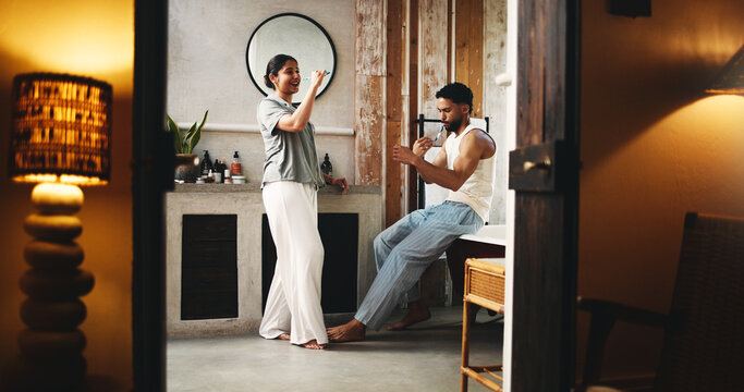 Couple, brushing teeth and singing in bathroom with smile for morning routine, humor or bonding together. Married people, clean mouth and karaoke with toothbrush, fun or healthy relationship in home.