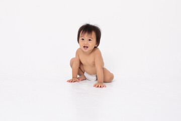 Asian playful baby family crawling on white studio floor smiling with curious expression wearing diaper joyful infant family moment