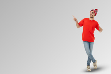 Young man wearing a red shirt and festive hat points to the side