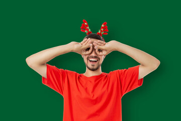 Smiling young man in festive red antlers covering eyes