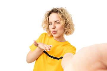 Girl in yellow shirt blows a kiss selfie, isolated on white, PNG
