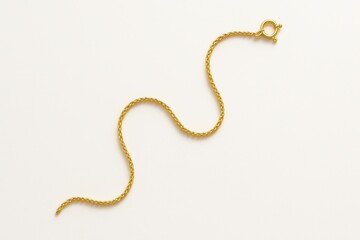 Top view gold chain neatly coiled in small circle beside digital caliper and blank white product card on bright white background