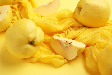 Composition with napkin, fresh quinces with cut pieces on yellow background, closeup