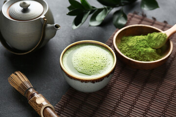 Composition with bowl of matcha tea on black grunge background, closeup