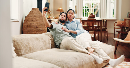 Happy couple, selfie and funny face on couch, home and post for memory, hug or relax in lounge. Woman, man and photography with joke on sofa, tongue out and playful bonding on social media at house