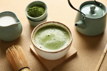 Composition with bowl of tasty matcha tea on beige grunge background, closeup