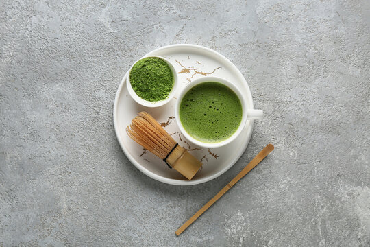Tray with cup of matcha tea and chasen on grey grunge background