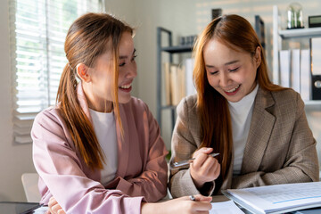 Businesswoman sitting at desk on couch in workplace or at home working on laptop and analyzing data on charts and graphs and writing on papers to make business plan and strategies for company, 