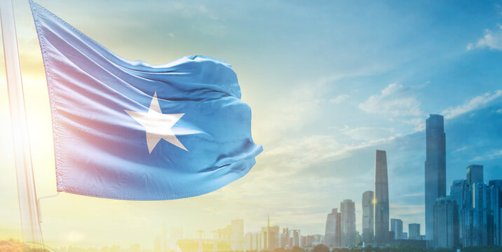 Somalia flag wavering in beautiful clouds with building skyline. The flag with drone shot in beautiful sky. Somalia national flag for independence day.