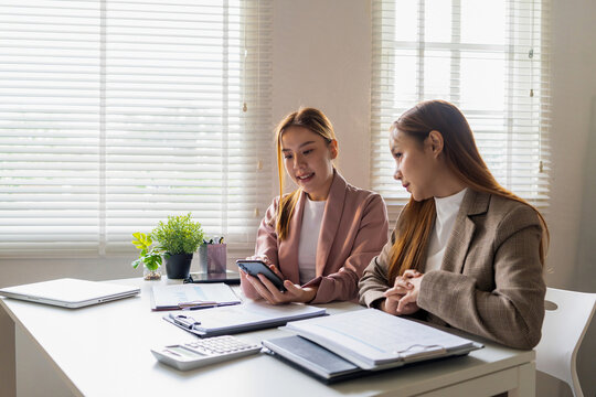 Businesswoman sitting at desk on couch in workplace or at home working on laptop and analyzing data on charts and graphs and writing on papers to make business plan and strategies for company,