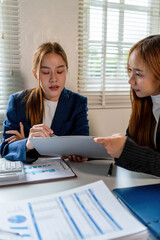 Businesswoman sitting at desk on couch in workplace or at home working on laptop and analyzing data on charts and graphs and writing on papers to make business plan and strategies for company, 