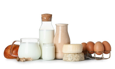 Different dairy products with eggs, bun and wheat spikelets on white background
