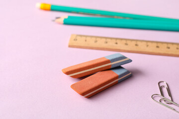Erasers with pencils and ruler on lilac background