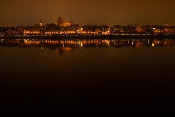 Toruń nocą, stare miasto nad rzeką Wisłą, światła odbijające się w wodzie.  © Elżbieta Kaps